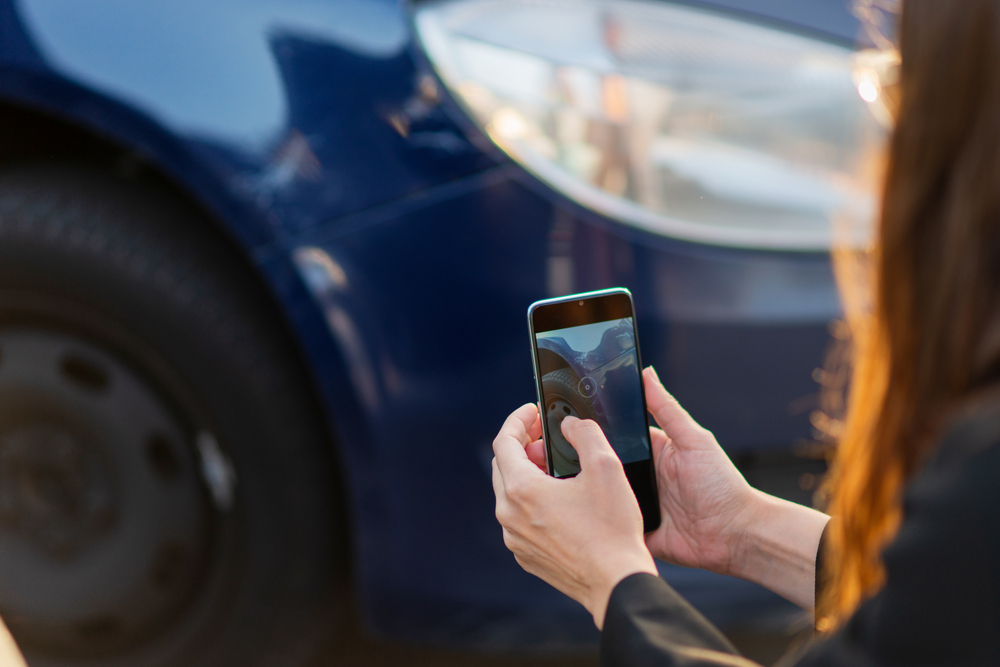Woman taking a picture after a car accident for documentation