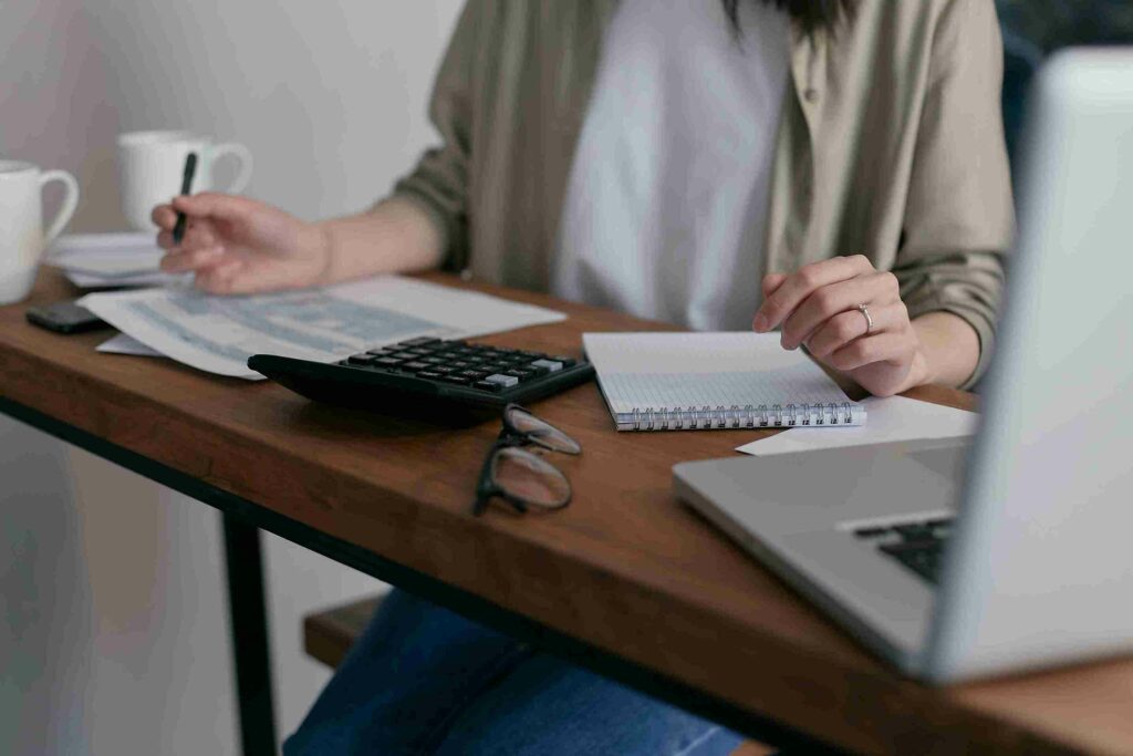 Woman handling finances with notebook and laptop