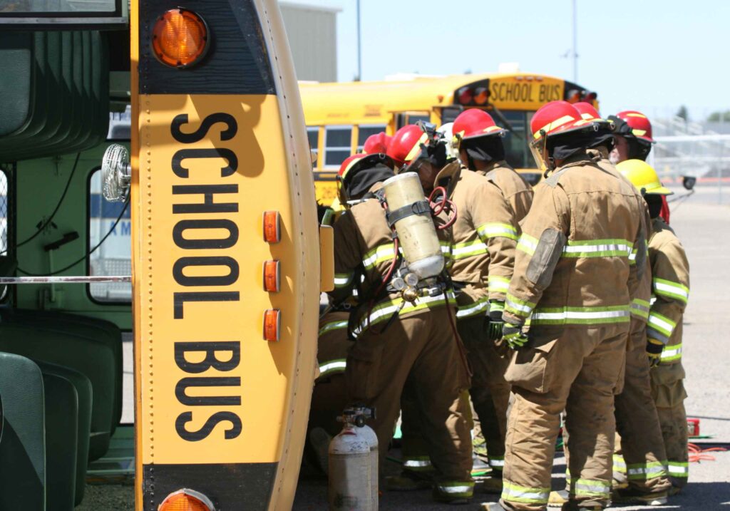 emergency responders rescuing the injured from an overturned school bus