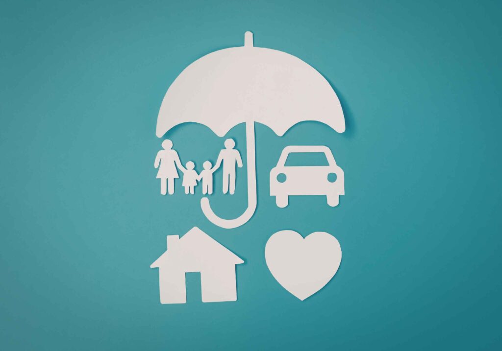 paper cutouts of family, car, house, and heart under an umbrella