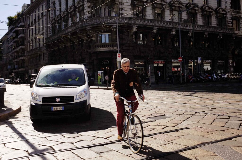 Cyclist riding through a city street with nearby van