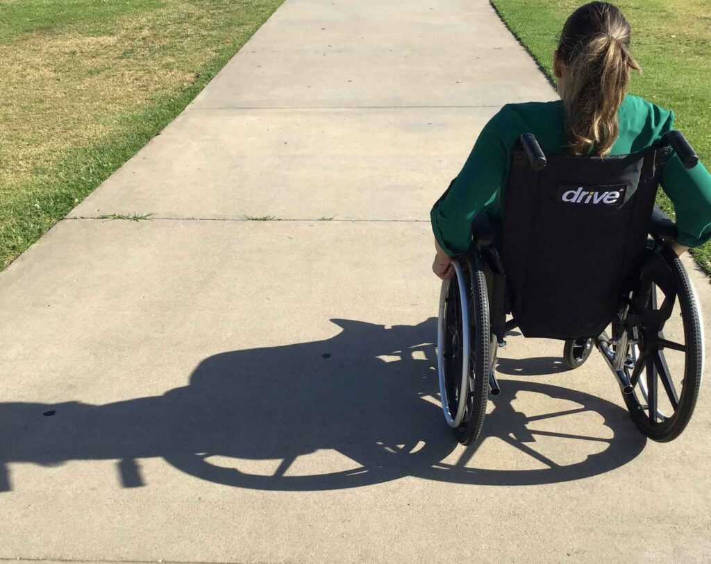 Wheelchair-bound lady moving along a paved path
