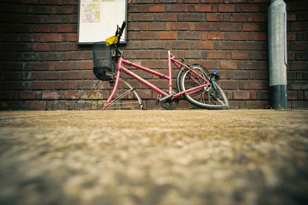 A broken bicycle leaning against a brick wall