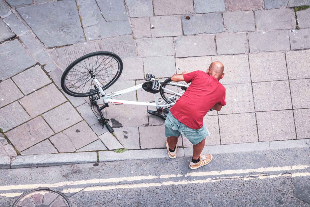 Man picking up a bicycle from the pavement